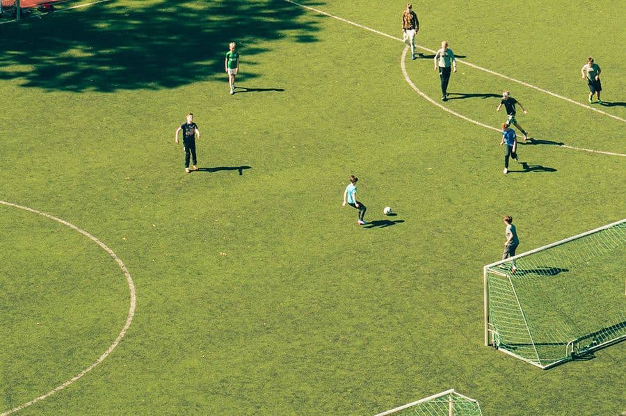 Fotbollsspelare på en solbelyst gräsplan sedd ovanifrån