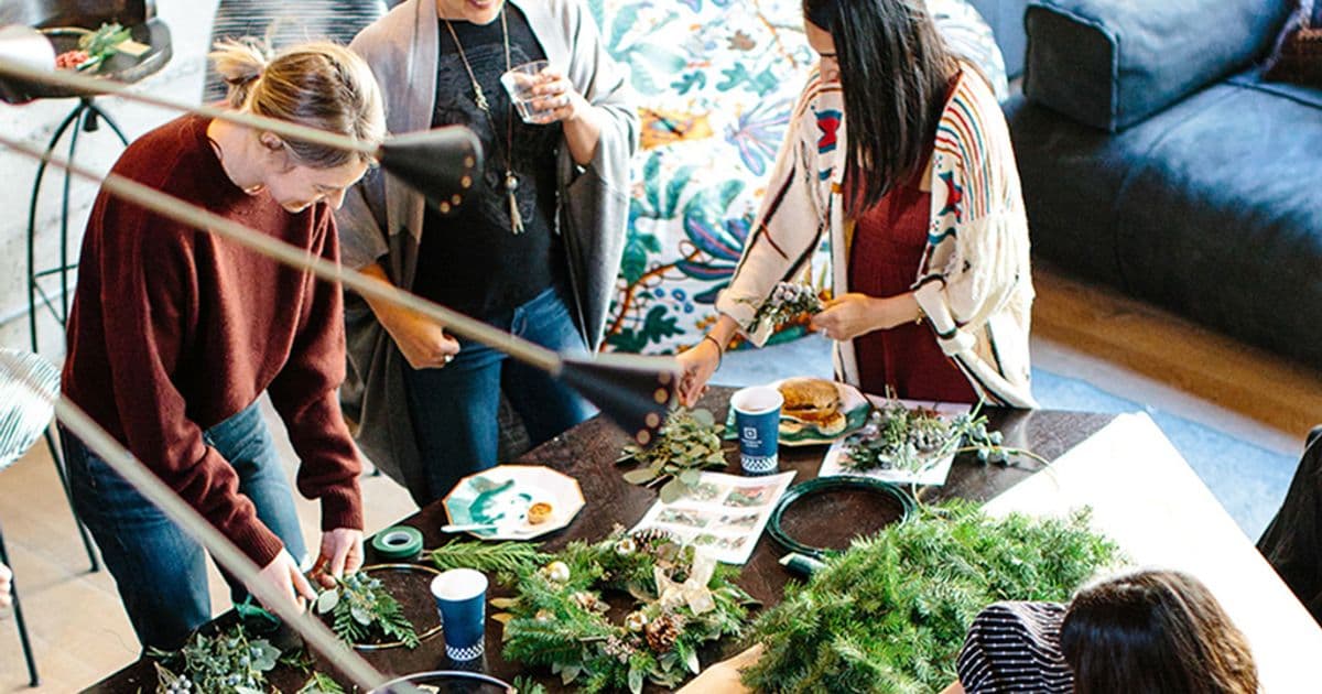 Friends gathered around a table with spruce twigs, greenery and food