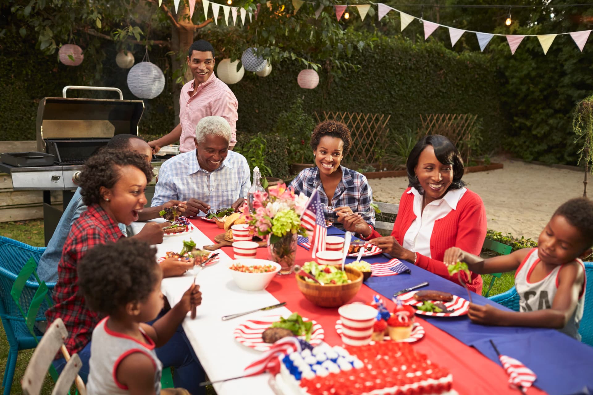 Family gathered around a set table in a garden with a barbecue