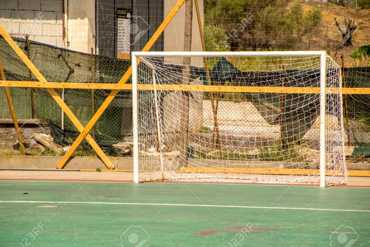 Football goal on a green pitch in front of a fence